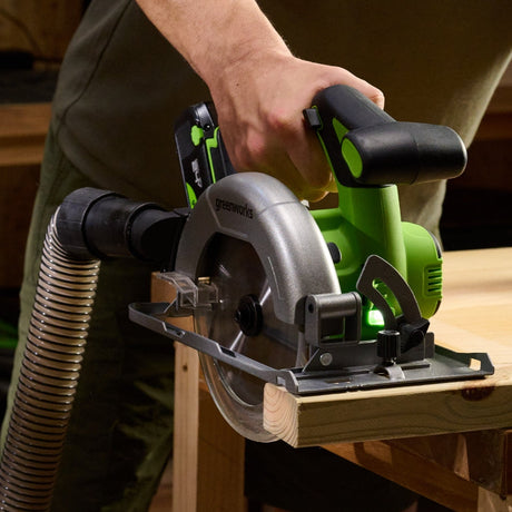 Person using a circular saw on a wooden workbench with a hose attached.
