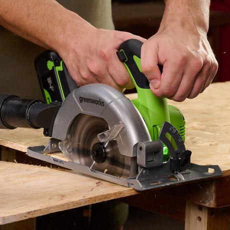 Person using a Greenworks circular saw on a wooden surface